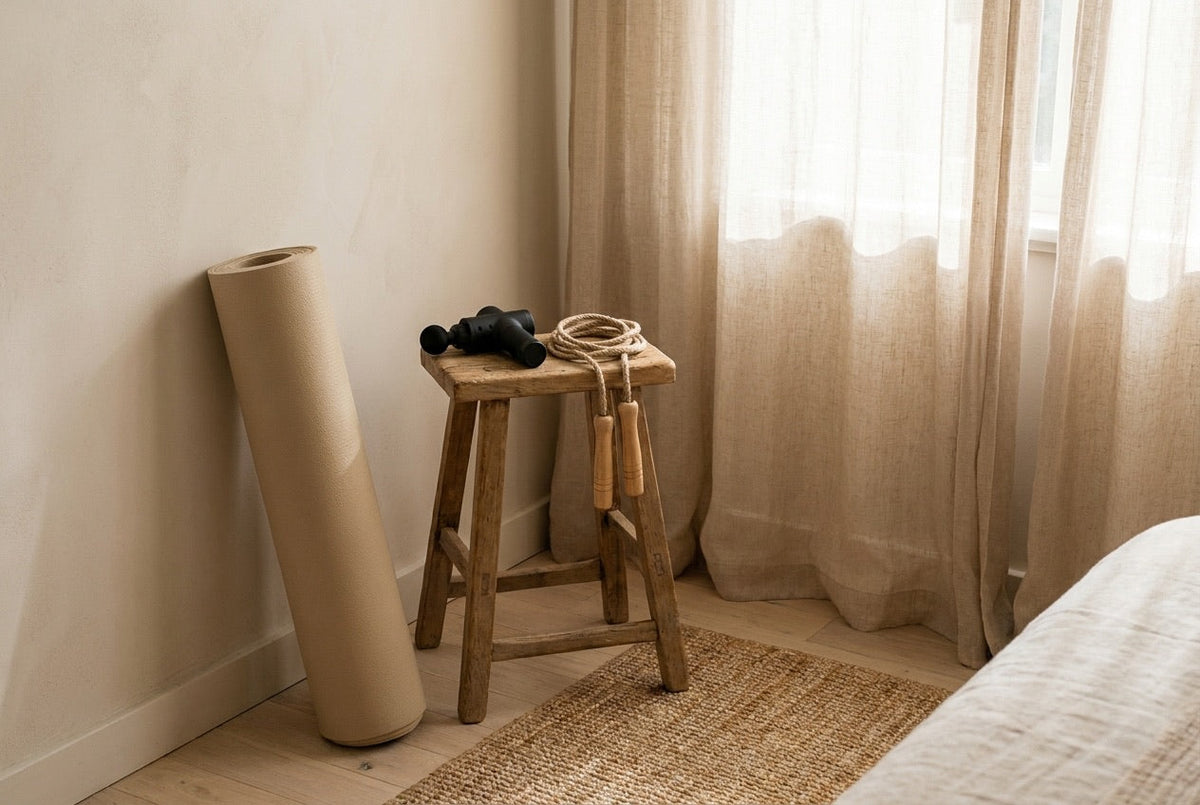 Exercise mat, mini massage gun and jump rope in a calm bedroom corner